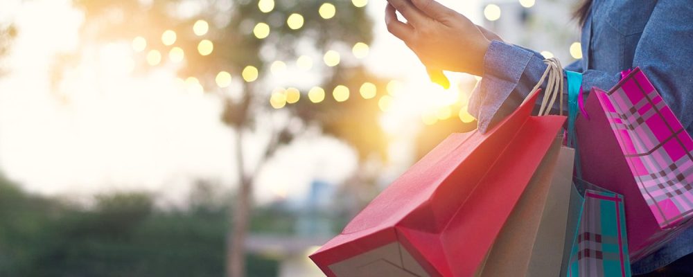 Woman using smartphone with shopping bag in hands